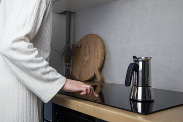 Young woman prepares coffee with mocha Cheerful girl in the kitchen prepares coffee on the induction stove
