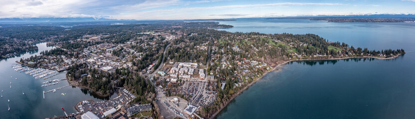 Panoramic Aerial view of Bainbridge Island City  in Kitsap County, located in the Puget Sound west of Seattle with old and modern buildings, harbor and mountains in the background