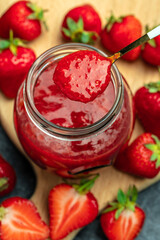 Strawberry jam in the glass jar, Homemade strawberry marmelade and fruits on a dark background, vertical image. top view. place for text