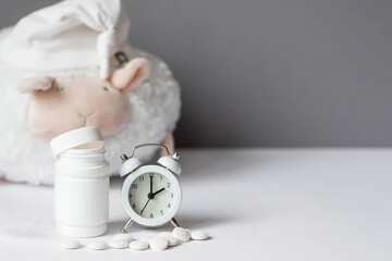 A tube of pills, a sheep in a sleep cap and an alarm clock. The time on the clock is 2 am. Insomnia...