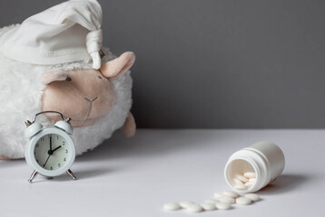 A tube of pills, a sheep in a sleep cap and an alarm clock. The time on the clock is 2 am. Insomnia...