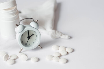 A tube of pills and an alarm clock. The time on the clock is 2 am. Insomnia and recovery of sleep...