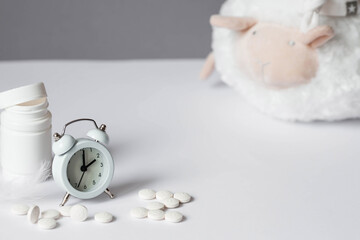 A tube of pills, a sheep in a sleep cap and an alarm clock. The time on the clock is 2 am. Insomnia...