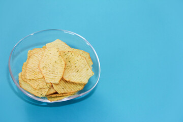 Yellow baked corrugated potato chips in a transparent plate