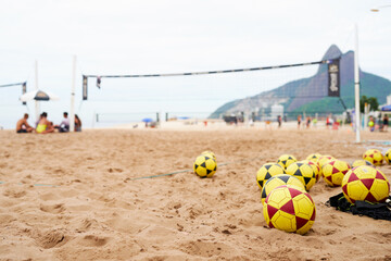 soccer balls on the field on the beach in Ipanema with people and beach in the background blurred