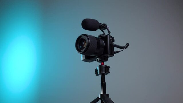 Close up of vlog setup with camera and microphone on tripod in vlogging studio. Led lights and camera on blue background