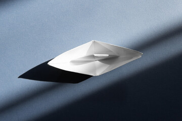 white origami boat on a blue background.