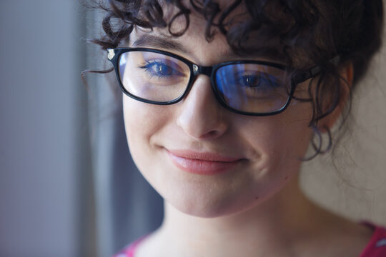 Portrait of cute brunette girl in glasses. Close up photo of cheerful young female person shot by the window at home