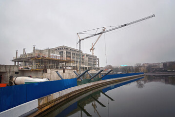 Building construction site against cloudy sky. Building construction on embankment in the city.