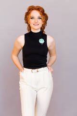 Beautiful brooch in the form of a clover on a black sleeveless jacket of a stylish red-haired girl.