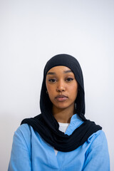 Portrait of young woman in hijab against white background