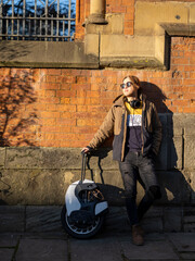 Portrait of man with electric unicycle against brick wall © Cultura Creative