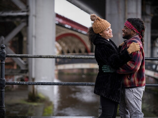 Smiling couple embracing near bridge