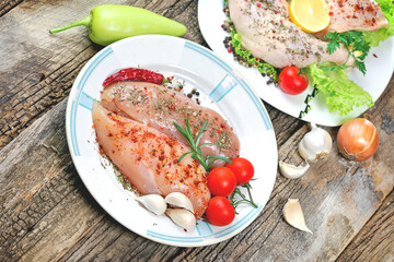 Raw chicken meat - raw chicken breast and raw chicken drumstick with spices on plate, on rustic table