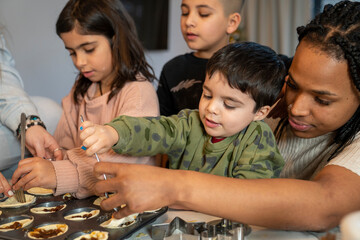 Moms with kids preparing Christmas muffins in kitchen