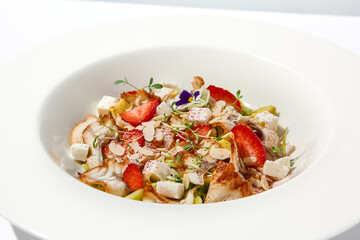 Elegant salad with smoked eel, strawberry and avocado on white table with harsh shadows. Eel salad with berries on white background with shadows of leaves. Romantic dining with fish appetizer.