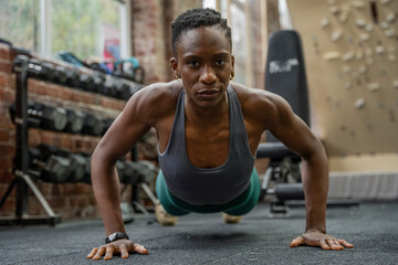 Fototapeta na wymiar Athletic woman doing push-ups at gym
