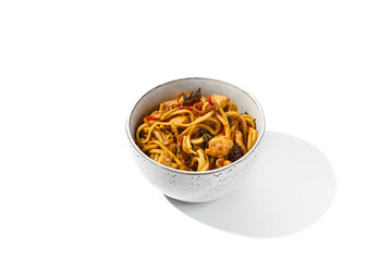 Asian fried noodles with chicken in sweet sour sauce isolated on white background Chinese fried noodles on wok in ceramic bowl. Stir-fry udon with chicken and vegetables in minimal style. Wok menu