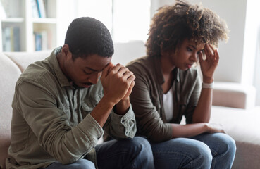 Upset african man and woman sitting on couch at clinic