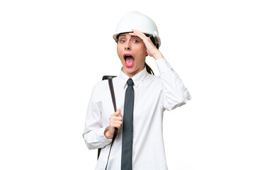 Young architect woman with helmet and holding blueprints over isolated background doing surprise gesture while looking to the side