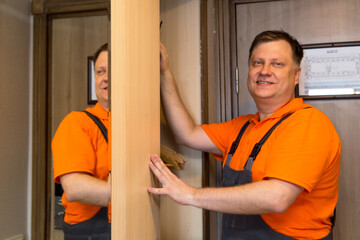 A male master in bright overalls installs a new wardrobe hotel.