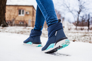 Winter puffy boots on female legs in winter on snow