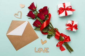 Valentines day gift box with red roses on color background, top view