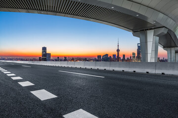 Asphalt road and bridge with city skyline at sunrise in Shanghai, China.