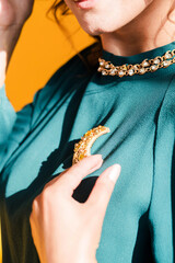 A golden brooch in the form of a month on a green blouse of a brunette girl. Young woman posing on...