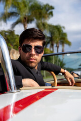 young man in a convertible car looking at camera, man driving car