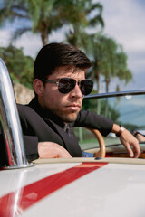 young man in a convertible car looking out to sea, man in car