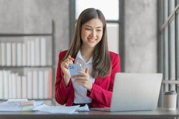 Fototapeta premium Beautiful asian accountant working with tablet computer in modern office with balance sheet, assets, stock market statistics, annual planning in office