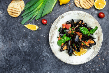Fine dining in a seafood restaurant: a big dish of mussels with bottle of white wine with two wine glasses, on dark background. Restaurant menu, dieting, cookbook recipe top view