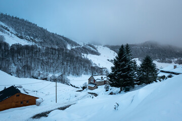 Algumas casas a meio de montanhas cobertas de neve próximo à instância de esqui em Gourette nos Pirenéus Atlânticos, França