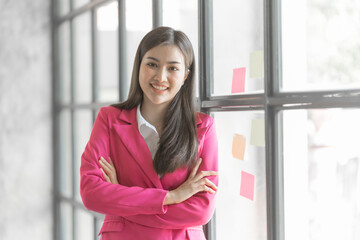 Pretty asia business woman bookkeeper brainstorming and working in modern office workplace with sticky notes or post it at windows.