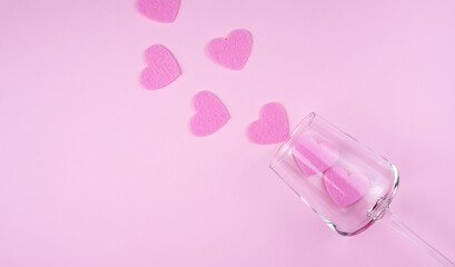 Flatlay composition with pink hearts and wineglass on the pink background. Valentine's day concept. Banner. Top view. Copy space. Selective focus.