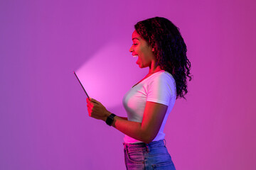 Surprised Black Woman Looking At Digital Tablet With Glowing Screen