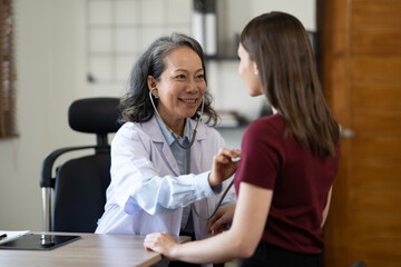 Fototapeta premium Professonal famale checking young woman heart rate. Medical care concept. .