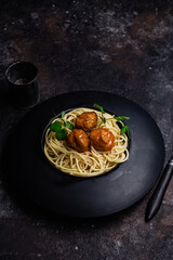 Spaghetti with meatballs in a black plate