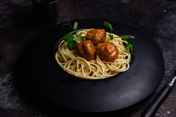 Spaghetti with meatballs in a black plate