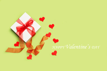 Mensaje del día de San Valentín con una caja de regalo y corazones rojos sobre un fondo verde...