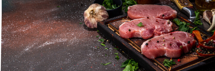 Raw pork steaks cooking background. Three tasty raw fresh meat steaks with herbs, salt, pepper,...