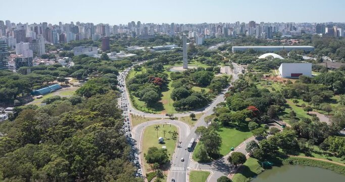Entrance to Ibirapuera Park, obelisk in the background, intense vehicle traffic. Bottom-up reverse drone flight on sunny day