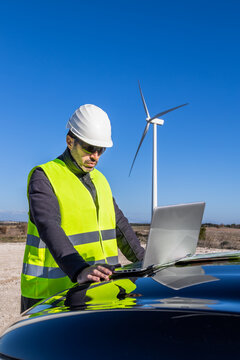 Male engineer examining map on hood of car