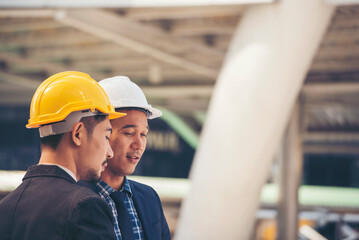 Civil Construction engineer teams shaking hands together wear work helmets worker on construction site. Foreman industry project working engineer teamwork. Two asian engineer team shake hands together