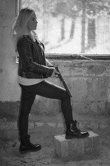 Beautiful girl with a pistol with a silencer in an abandoned building.  Black and white photo.