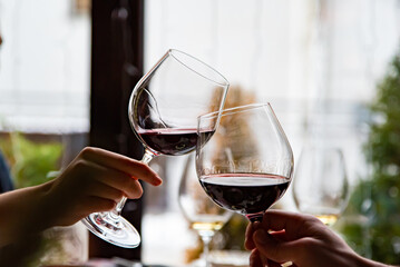 Close up of hands young couple clinking with glasses of red wine at restaurant