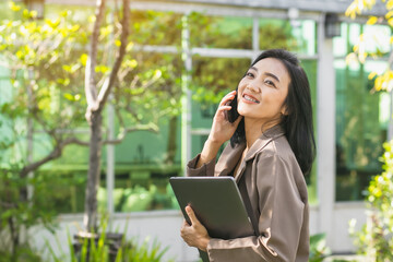 Young beautiful Asian woman working with smartphone and  laptop, She used the internet and shopped online in the garden, freelancer working businesswoman lifestyle concept