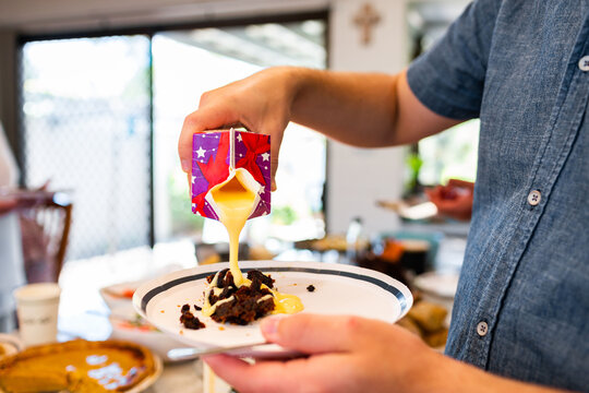 Man pouring custard onto traditional Christmas pudding