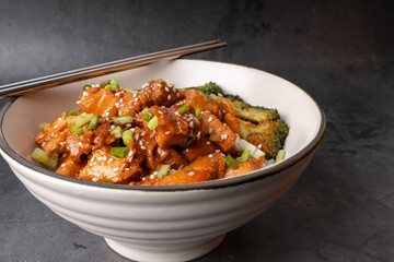 Chopsticks with Delicious sweet chopping chicken rice, sesame seeds, sliced spring onions, broccoli, and vegetables. Asian food, Japanese food.